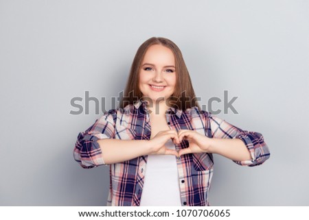 Portrait of lovely pretty stylish model in checkered shirt gesturing love symbol heart figure with fingers isolated on grey background, health care heart attack fast food unhealthy lifestyle concept