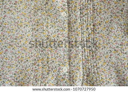 White buttons with colored threads on floral fabric background