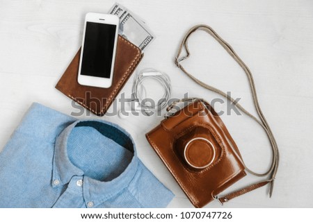 travelers outfit on white wooden textured background with film camera passport shirt and money