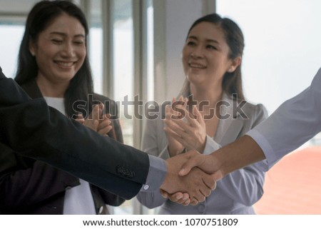 Picture of businessman shaking hands over a deal negotiation to success with team clapping their hands at workplace office