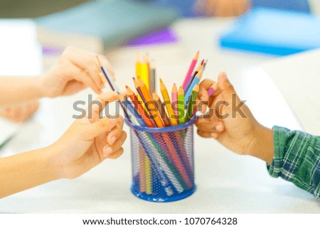 Group of little kids hands choosing colorful crayons in pencil holder for drawing and painting their picture during recreation class at school. Kindergarten teaching children to develop their skill.
