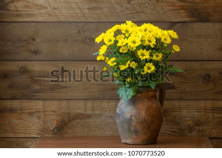Beautiful yellow chrysanthemum flowers in a vase on wooden background