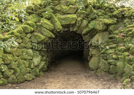 Stone, man made entrance to a dark cave.  Rocks covered in moss