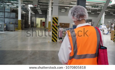Follow footage of factory worker in a hard hat that is walking through industrial facilities. Clip. Following Shot of Female Industrial Worker in the Hard Hat Walking Through Heavy Industry