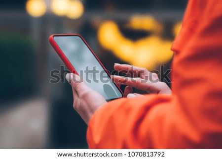 Cropped view of woman using mobile phone applications with internet connection. Female hands holding modern smartphone on city street. Social network content, internet traffic data. Free wireless 