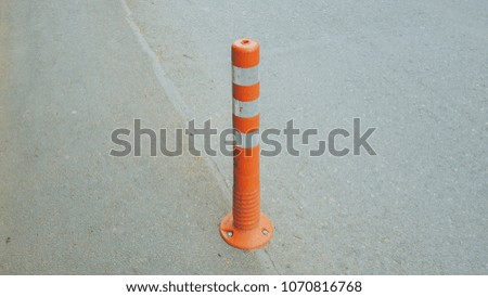 orange and white safety delineator on an empty road