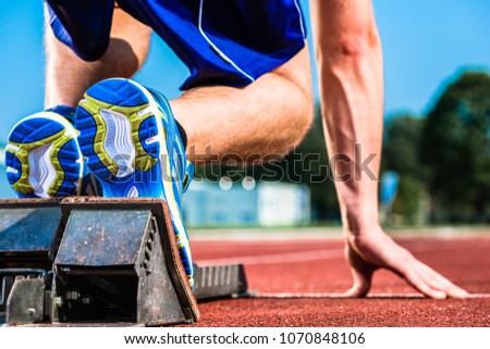 Runner before start signal on starting block of sprint track in sport stadium Royalty-Free Stock Photo #1070848106