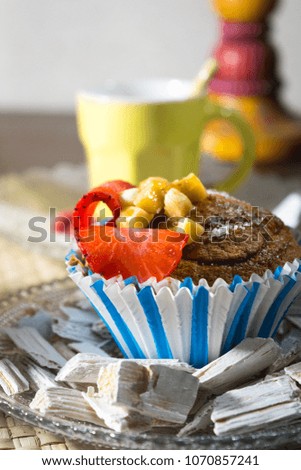 Cupcake with banana and strawberries with a cup of coffee and milk at the background of the image
