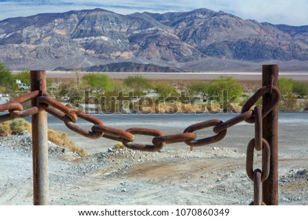 Huge rusty anchor chain hanging between two posts.