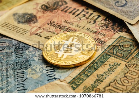 Colorful germany currency and bank notes shot close up with golden Bitcoin. Old paper money. Cryptocurrency and blockchain concept background. Closeup, copy space.