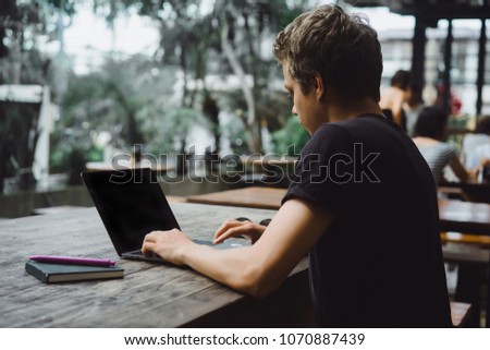 man working at a laptop in a cafe on a wooden table, hands of a man working on a computer, smartphone, notebook, desktop.