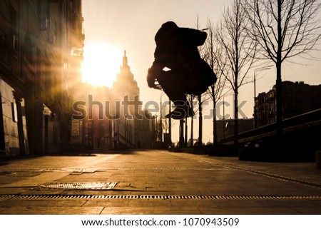 man portrait jumping motion in the urban city streets during sunset silhouette