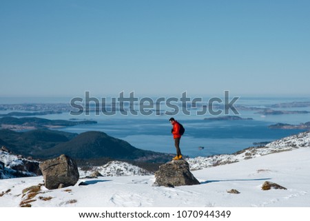 Picture of a traveling hiker man standing on the rock near the Preikestolen in Norway. Traveler enjoyoing the scenic panorama view. View from above