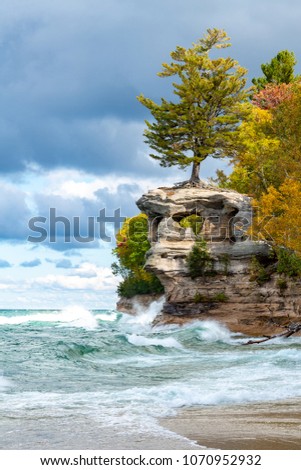 A stormy Lake Superior drives waves crashing against Chapel Rock as ominous skies and autumn colors create a stunning background