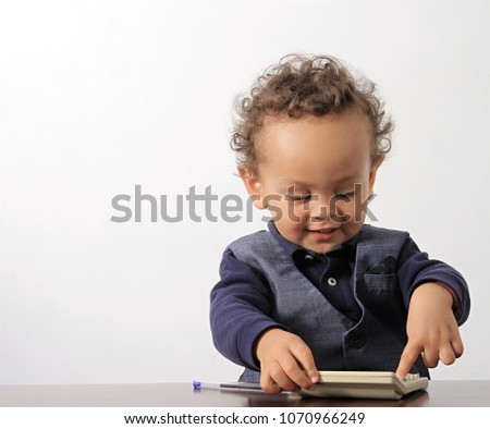 little boy playing with calculator on table with pen at pre school stock photo