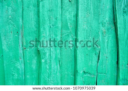 Texture of a green wooden wall, a fence of vertical bright boards of different sizes. Bright green lime boards with cracks and knots background