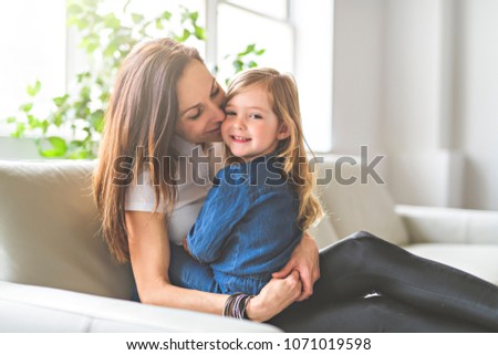 Portrait of a beautiful mother and her little girl sitting at home