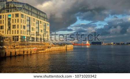 Late afternoon landscape. The skyline glows under an orange sunset light. The ship is moving along the river