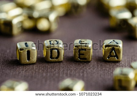 Word IDEA made from small golden letters on the brown background, selective focus