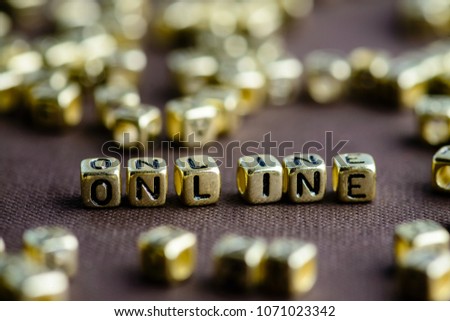 Word ONLINE made from small golden letters on the brown background, selective focus