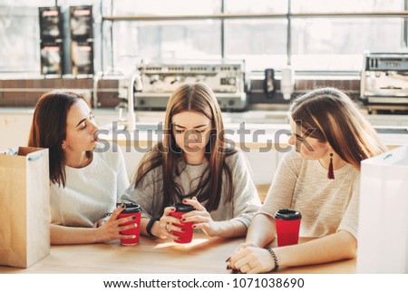 Best friends trying to comfort and cheer up young depressed woman after break up sitting at the table at cafe. Three women drink coffee at the mall Royalty-Free Stock Photo #1071038690