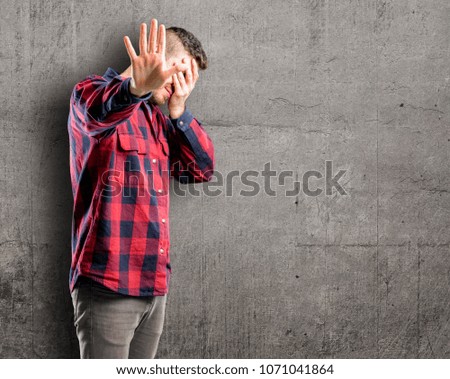 Young handsome man stressful and shy keeping hand on head, tired and frustrated