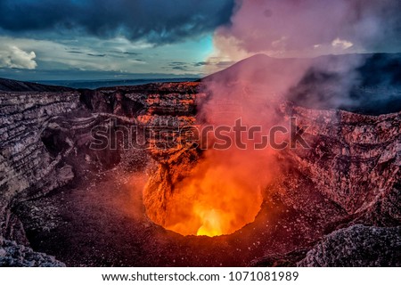 Volcano crater eruption with flowing lava and smoke.  The Masaya Volcano near Managua, Nicaragua main crater after sunset. Royalty-Free Stock Photo #1071081989