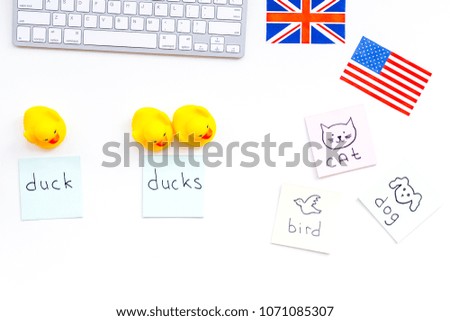 Teach english to a child. Funny english. British and american flags, computer keyboard, stickers with vocabulary, toy duck on white background top view