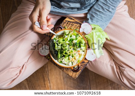 Woman hands holding fresh summer salad with raw vegetables cabbage, spinach, radish, parsley, greens in bowl for dinner or lunch. Vegan vegetarian healthy food. Royalty-Free Stock Photo #1071092618