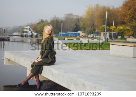 young and stylish girl sitting in the autumn park near water