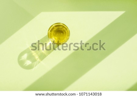 Pear lemonade in transparent glass Cup in the sun with shadow on green background