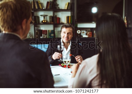 Back view image of male and female businesspeople. Talking at restaurant to partner sitting before.