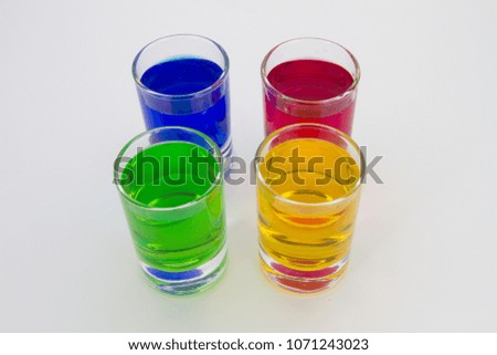 Multicolored glasses of different drinks. Party and holiday celebration concept. Four glasses with a blue, green, yellow and red drink. Isolated on white background.