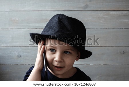 a little boy in a hat holds a phone