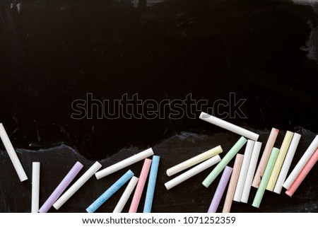 Group of multicolored chalks on black chalkboard.