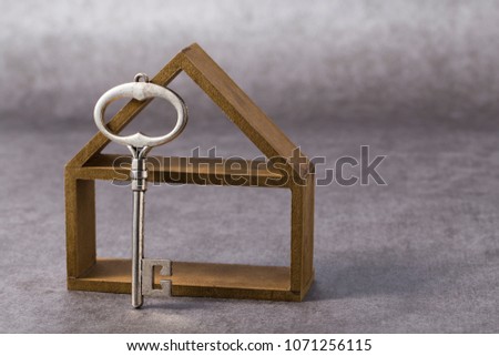 Symbol of the house with silver key on grey background Royalty-Free Stock Photo #1071256115