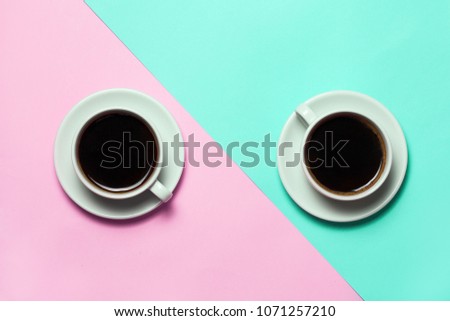 Two cups of coffee on minimalistic blue and pink background. Top view, flat lay. Minimalism coffee concept.