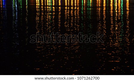Colored night city lights on water surface