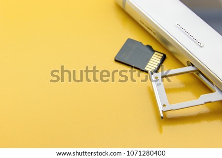 Flash memory data storage concept : A tray with a micro SD card on yellow background. A memory card is used for storing digital information in portable electronic devices e.g mobile phone, tablets etc