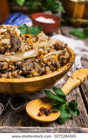 Traditional buckwheat porridge with meat and vegetables in bowl on wooden background. Selective focus.