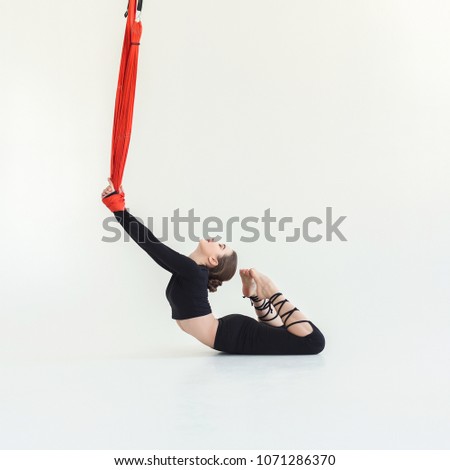 Young slim woman practicing fly yoga asana and stretching over white background in fitness gym, copy space. Health, sport, yoga concept