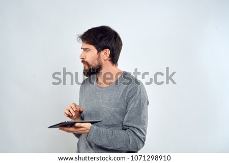   man with a beard looks at a place free in his hand holds a tablet                             