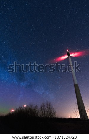 Beautiful night stary sky with milky way and an electrical wind turbine.