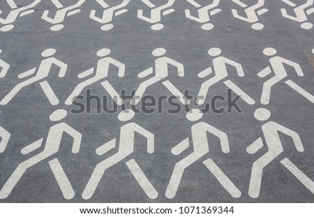 white pictograms of people walking in rows on the asphalt