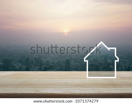 House icon with copy space on wooden table over aerial view of cityscape at sunset, vintage style, Real estate concept