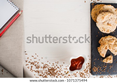 Flat tortillas made from whole-wheat flour on a stone dish with red tomato sauce on white wooden table of boards  and a notebook with pencils for notes