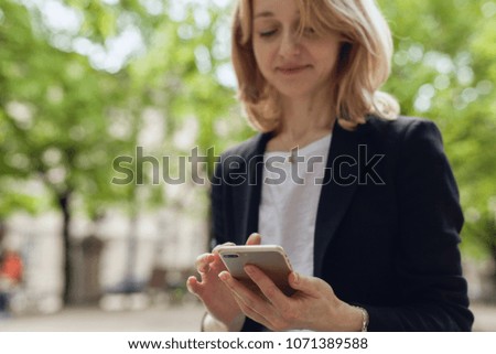 Close up image of smiling businesswoman using modern smartphone device, female hands holding mobile phone in park, successful female entrepreneur using cellphone wireless connection for work