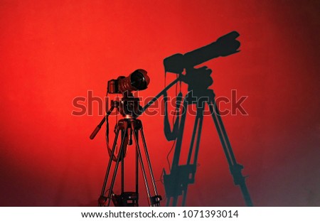 camera on a tripod, camera shadow on the wall, red background, concept shooting process, blogging
