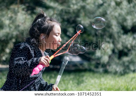 Lovely young asian girls blow bubbles outdoors