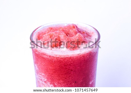 Red fruit flavored frozen cocktail or smoothie beverage, drink of strawberry and tomato smoothie isolated on white background, Healthy drink